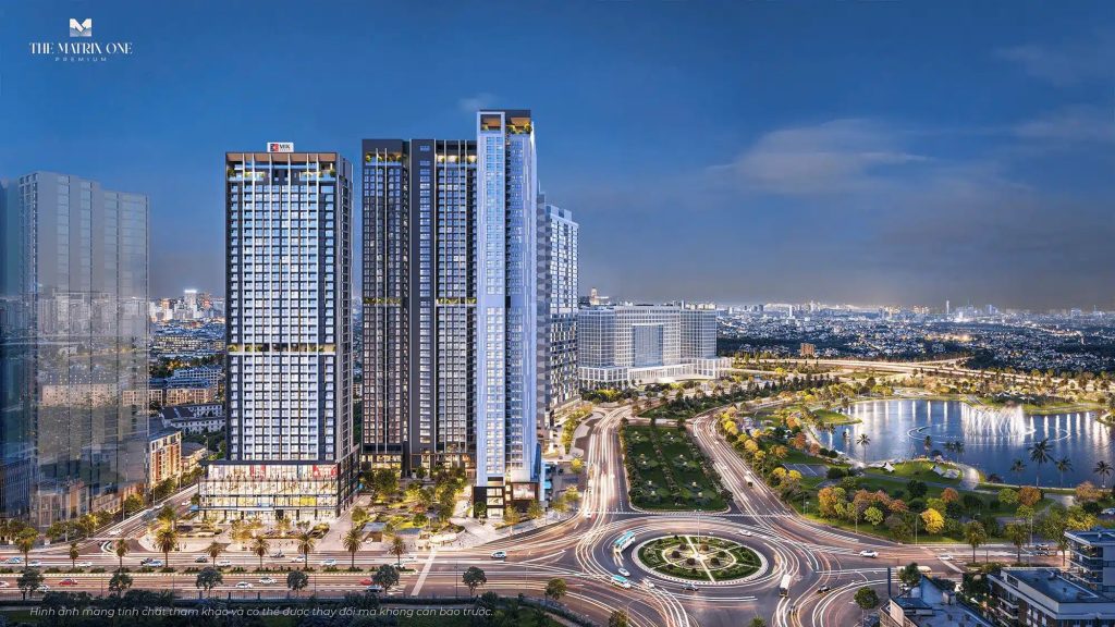 Tiến độ thi công Vinhomes Nguyễn Trãi - Cập nhật mới nhất 2 Hình ảnh toàn cảnh Vinhomes Nguyễn Trãi, với 2 tòa tháp hiện đại có cửa sổ sáng đèn vào lúc hoàng hôn, xung quanh là vòng xoay nhộn nhịp, cây xanh tươi tốt và một hồ nước yên bình, với khung cảnh thành phố Hà Nội ở phía xa.